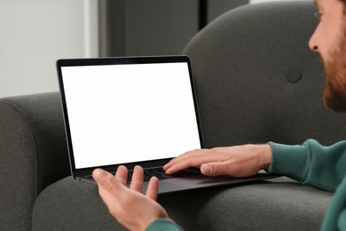 Photo of Man using laptop on grey couch, closeup