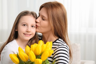 Photo of Mother and her cute daughter with bouquet of yellow tulips at home