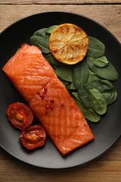 Photo of Tasty grilled salmon with tomatoes, lemon and basil on wooden table, top view