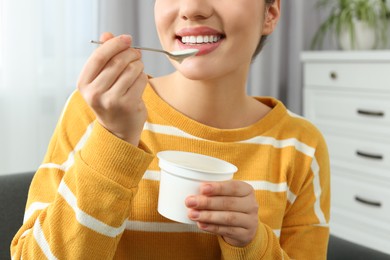 Photo of Happy woman eating tasty yogurt at home, closeup