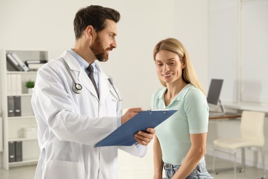 Photo of Doctor with clipboard consulting patient in clinic