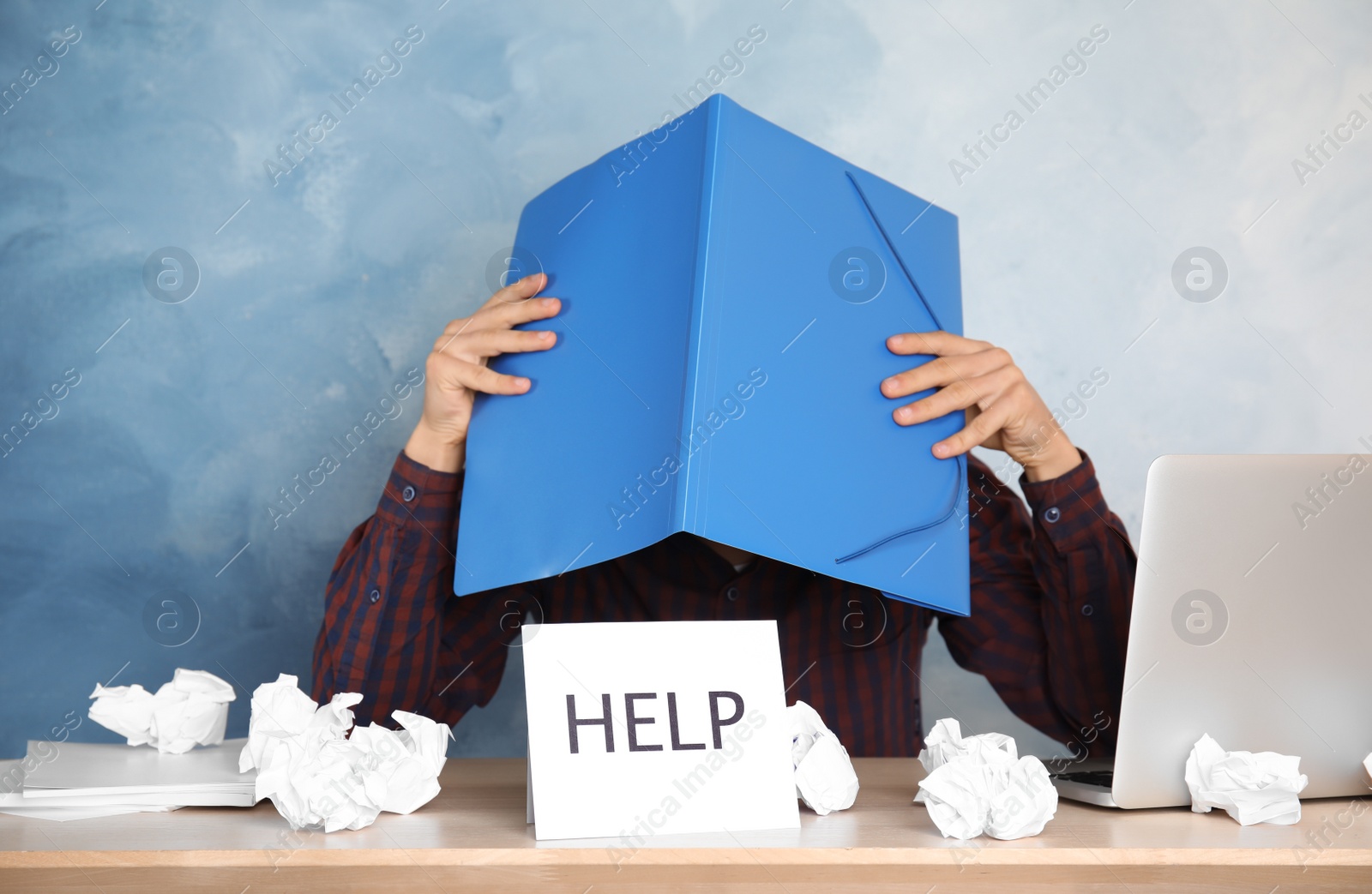 Photo of Man covering head with folder at table in office. Asking for help