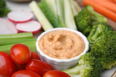 Photo of Plate with delicious hummus and fresh vegetables, closeup