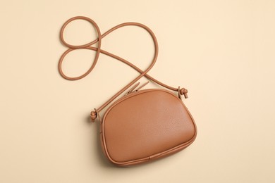 Stylish leather handbag on beige background, top view