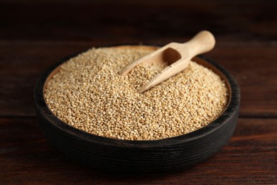 Photo of Plate with white quinoa and scoop on wooden table