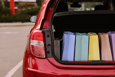 Photo of Shopping bags in car trunk outdoors, closeup