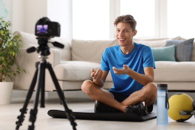 Photo of Smiling sports blogger recording fitness lesson with camera at home