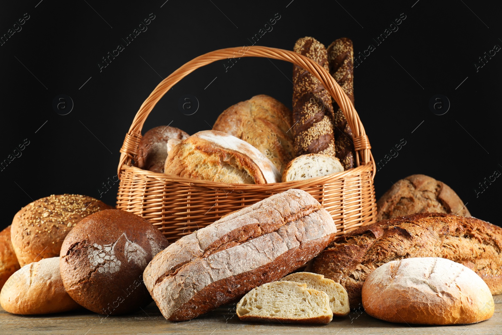 Photo of Wicker basket with different types of fresh bread on wooden table