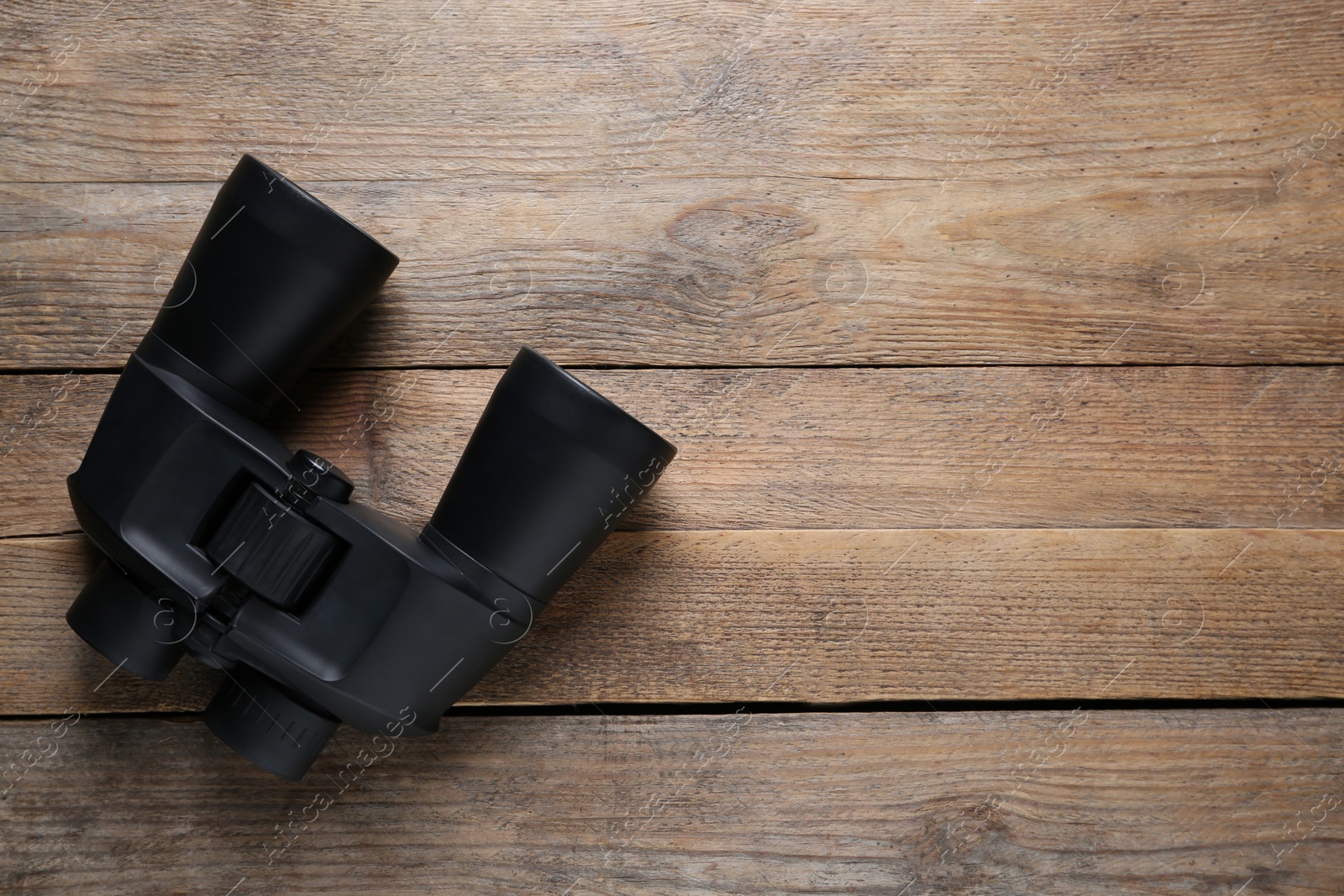 Photo of Modern binoculars on wooden table, top view. Space for text