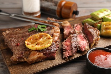 Delicious grilled beef steak and vegetables served on wooden table, closeup