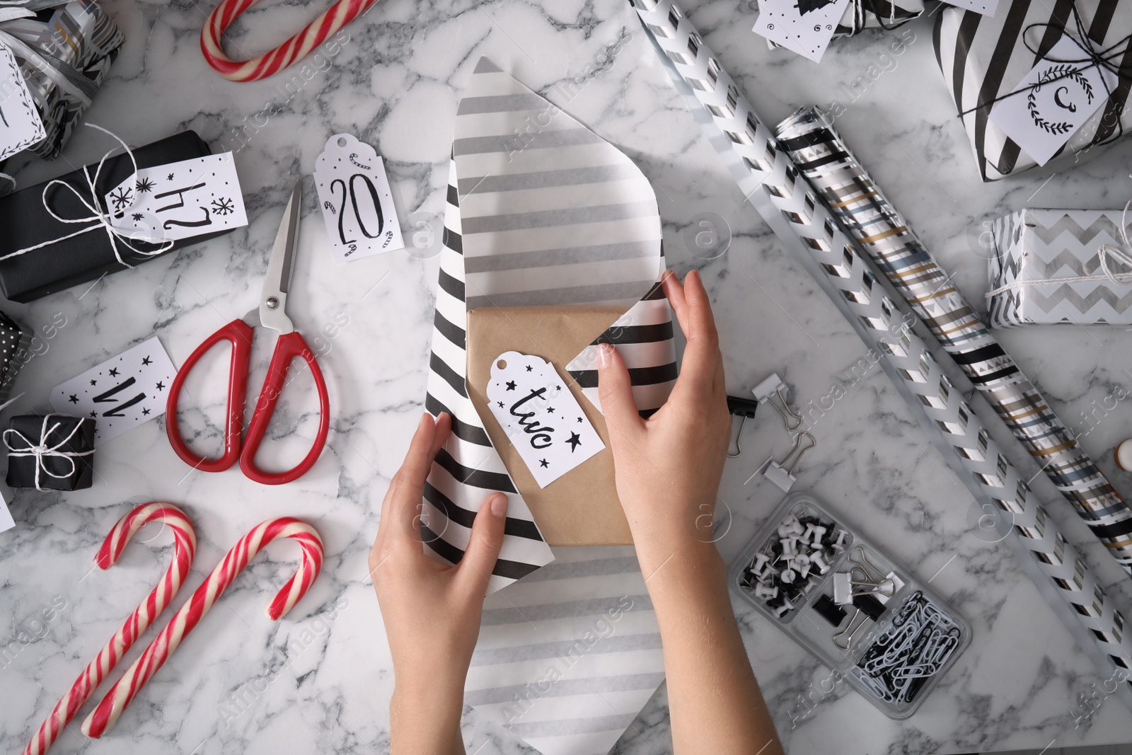 Photo of Woman making advent calendar at white marble table, top view