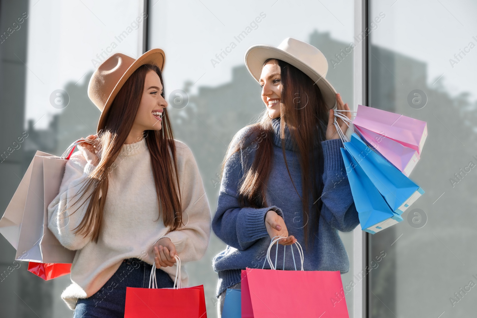 Photo of Beautiful young women with shopping bags near building outdoors