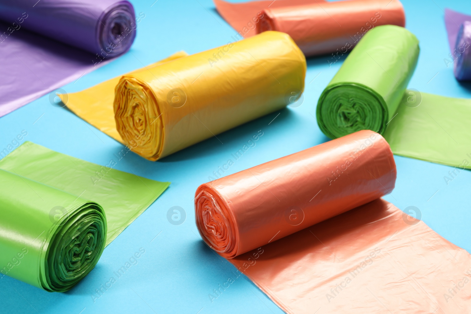 Photo of Rolls of different garbage bags on light blue background