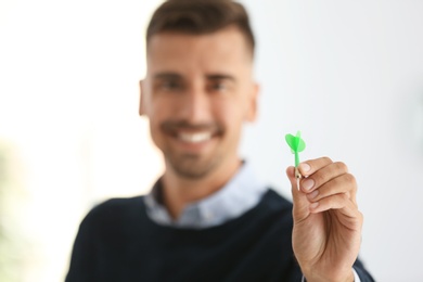Photo of Happy young businessman in office, focus on hand with dart