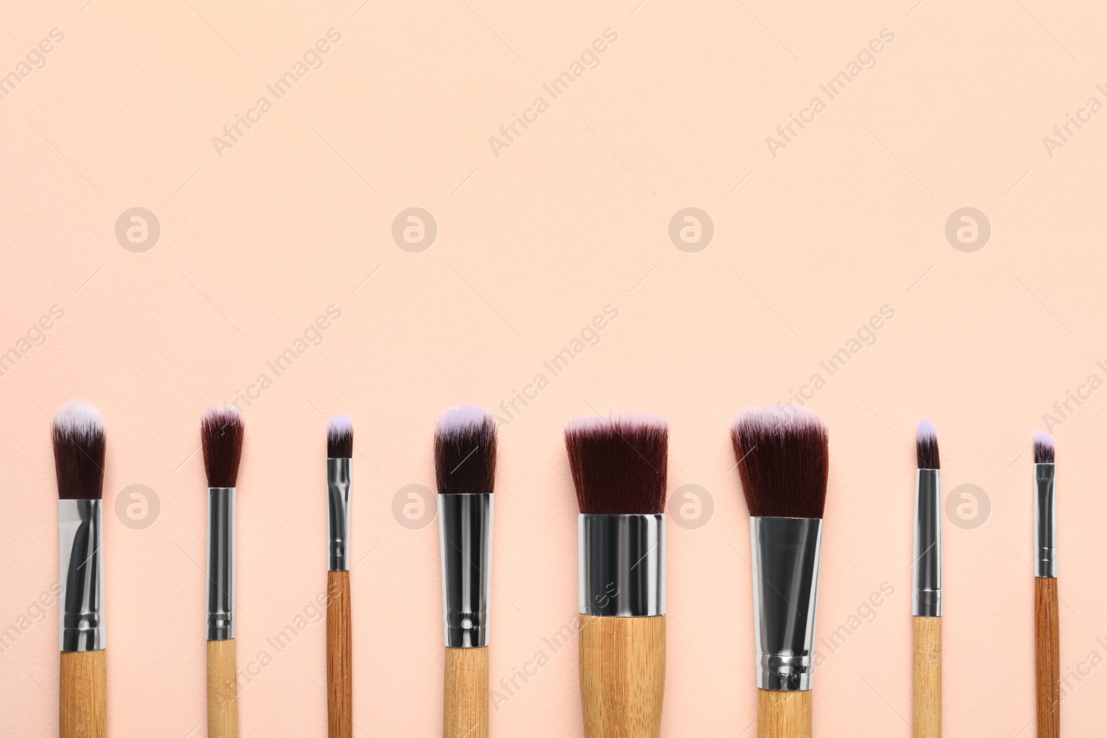 Photo of Set of makeup brushes on beige background, flat lay. Space for text