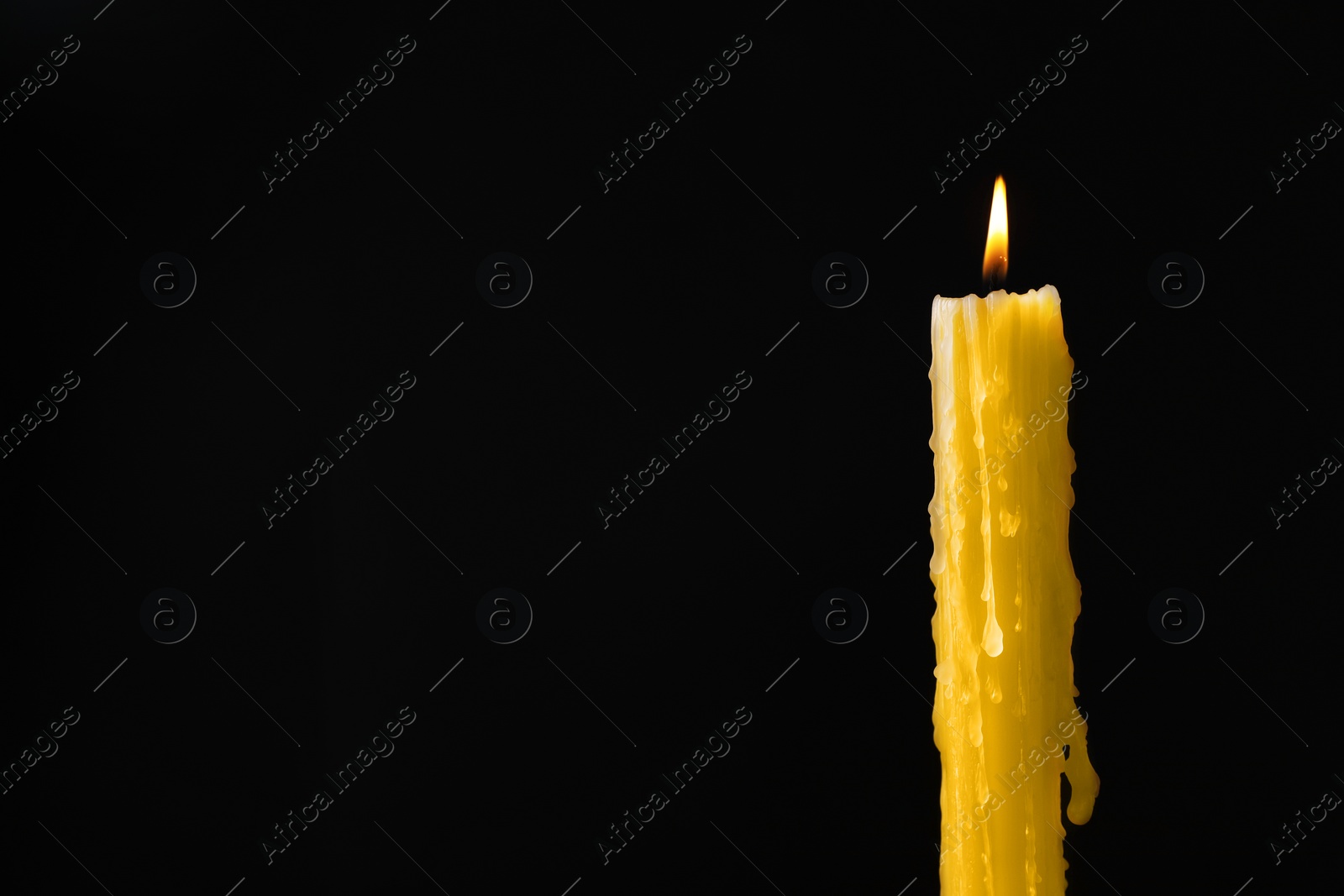 Photo of Burning church wax candle on black background, space for text