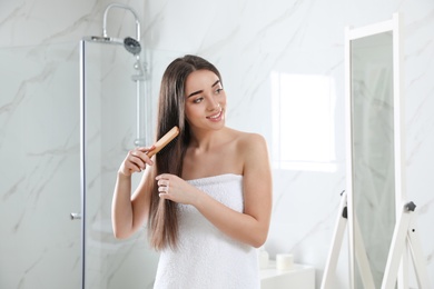 Photo of Beautiful young woman with hair brush in bathroom