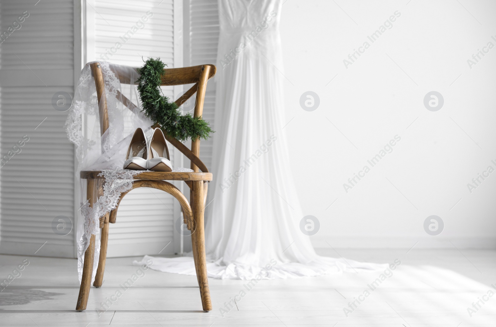 Photo of Pair of white high heel shoes, veil and wedding dress indoors. Space for text