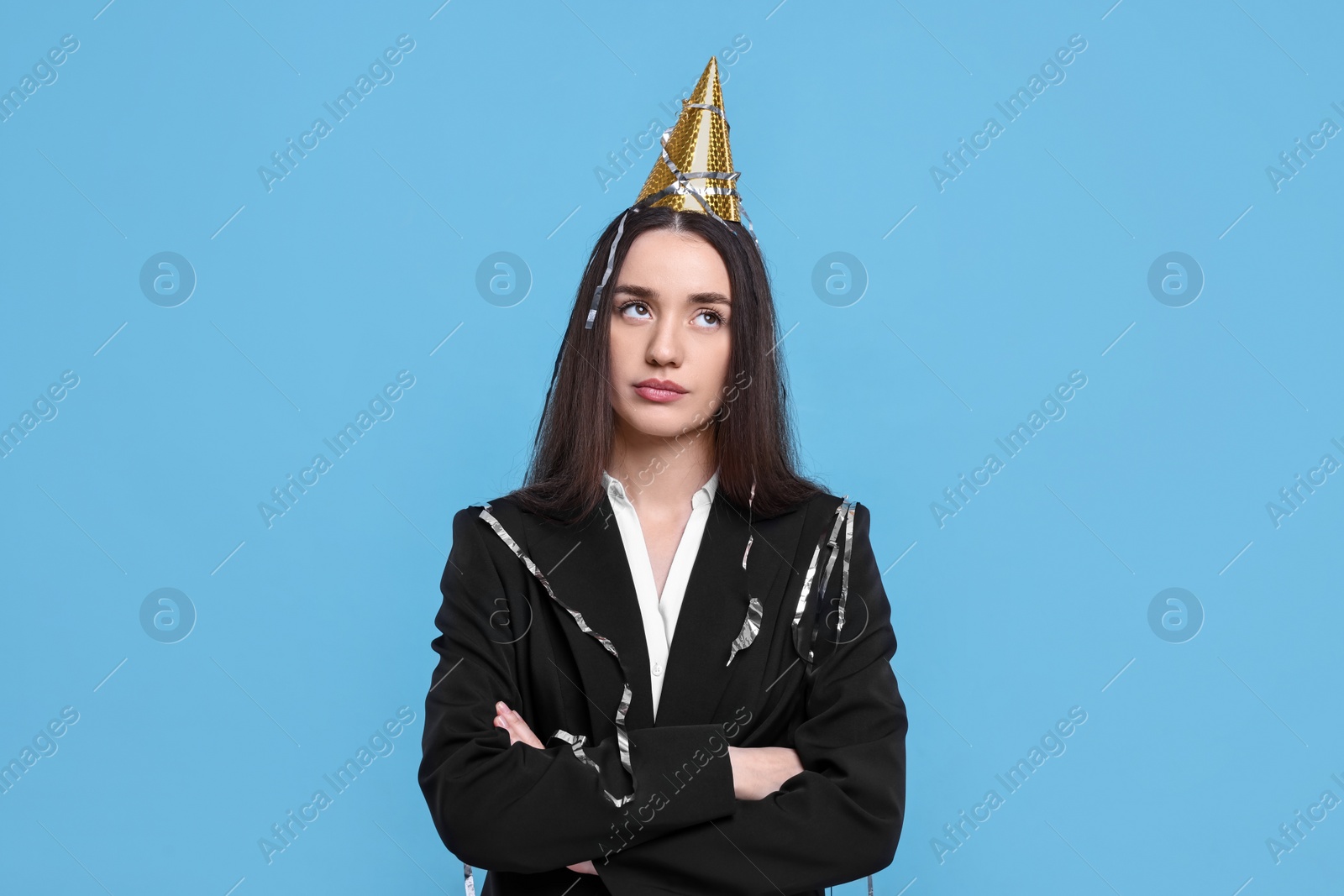 Photo of Sad woman in party hat on light blue background