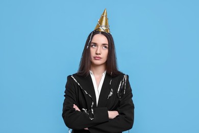 Photo of Sad woman in party hat on light blue background