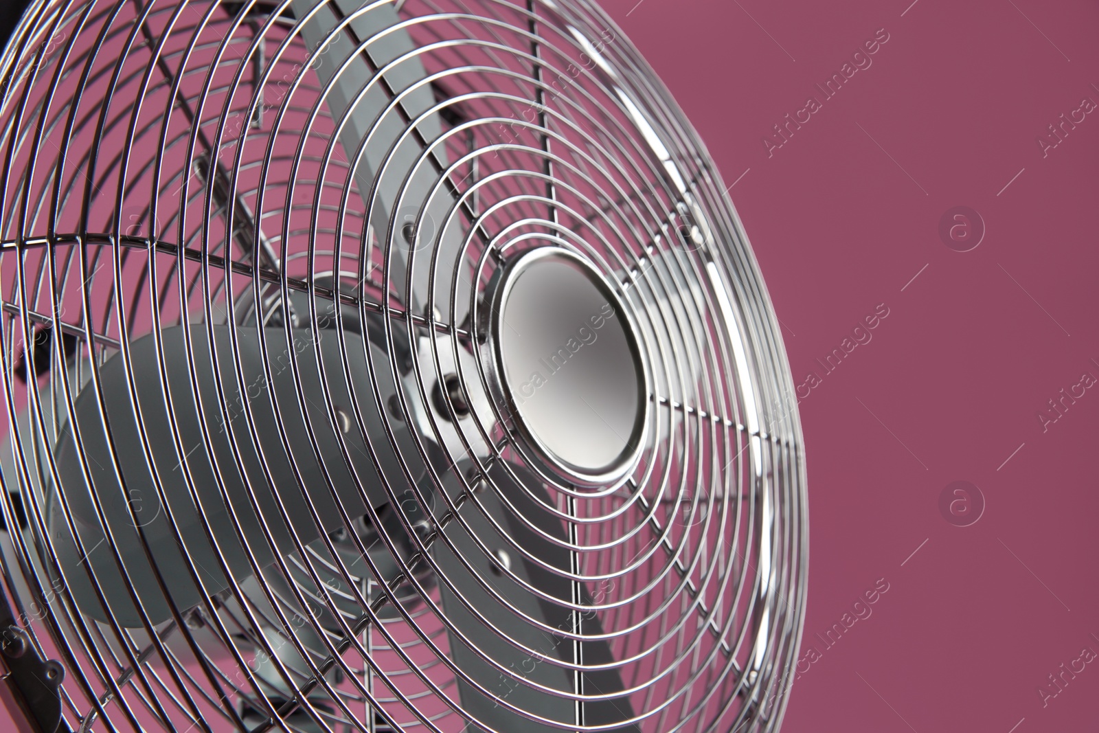 Photo of Modern electric fan on pink background, closeup