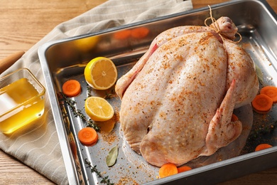 Photo of Baking dish with raw spiced turkey on table