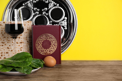 Photo of Symbolic Pesach (Passover Seder) items on wooden table against yellow background