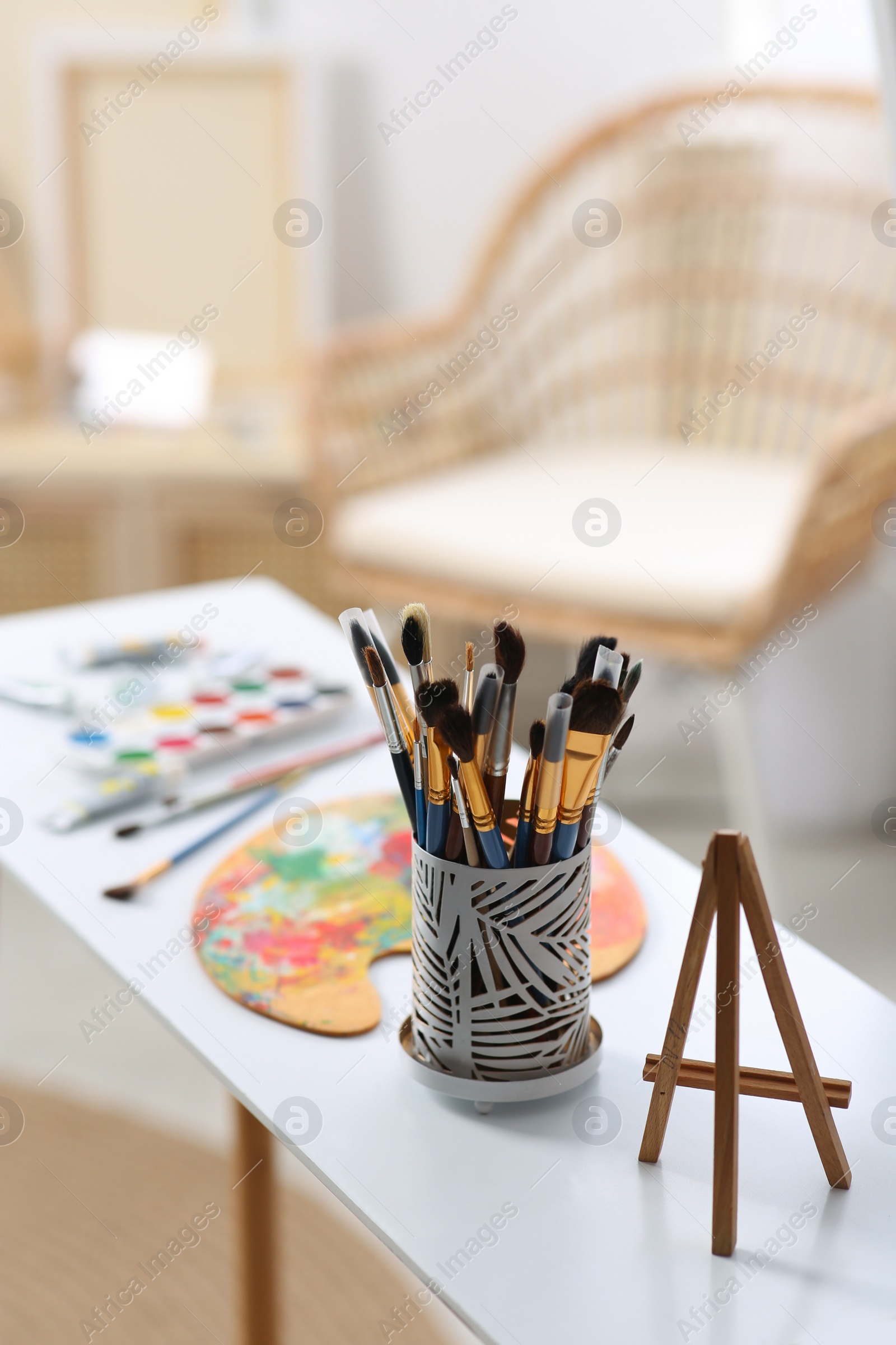 Photo of Brushes and small easel on table in art studio