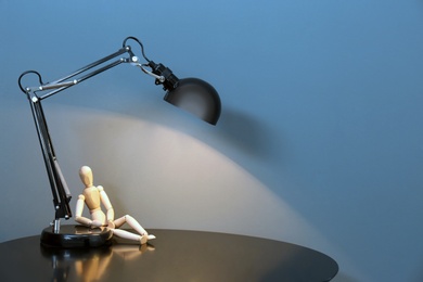 Photo of Modern lamp on table against color background. Space for text