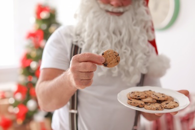 Authentic Santa Claus with plate of cookies indoors