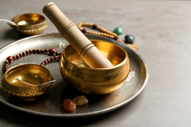 Composition with golden singing bowl and mallet on grey table, closeup. Sound healing