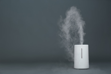 Photo of Modern air humidifier on grey background. Space for text