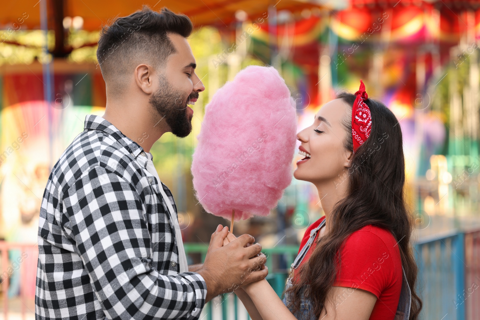 Photo of Happy couple eating cotton candy at funfair