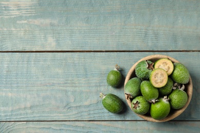 Flat lay composition with fresh green feijoa fruits on blue wooden table, space for text