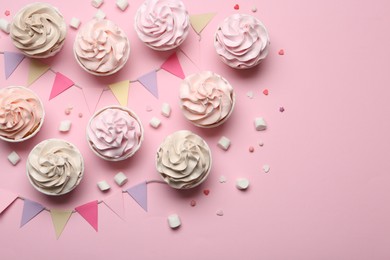 Photo of Delicious birthday cupcakes, bunting flags, marshmallows and sprinkles on pink background, flat lay. Space for text