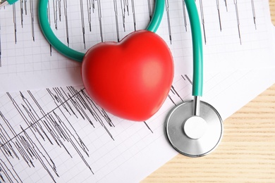 Photo of Stethoscope, red heart and cardiograms on table, top view. Cardiology concept