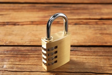 Photo of One steel combination padlock on wooden table, closeup