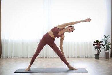 Photo of Young woman practicing triangle asana in yoga studio. Trikonasana pose