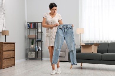 Young woman with just unpacked new jeans at home. Online shopping