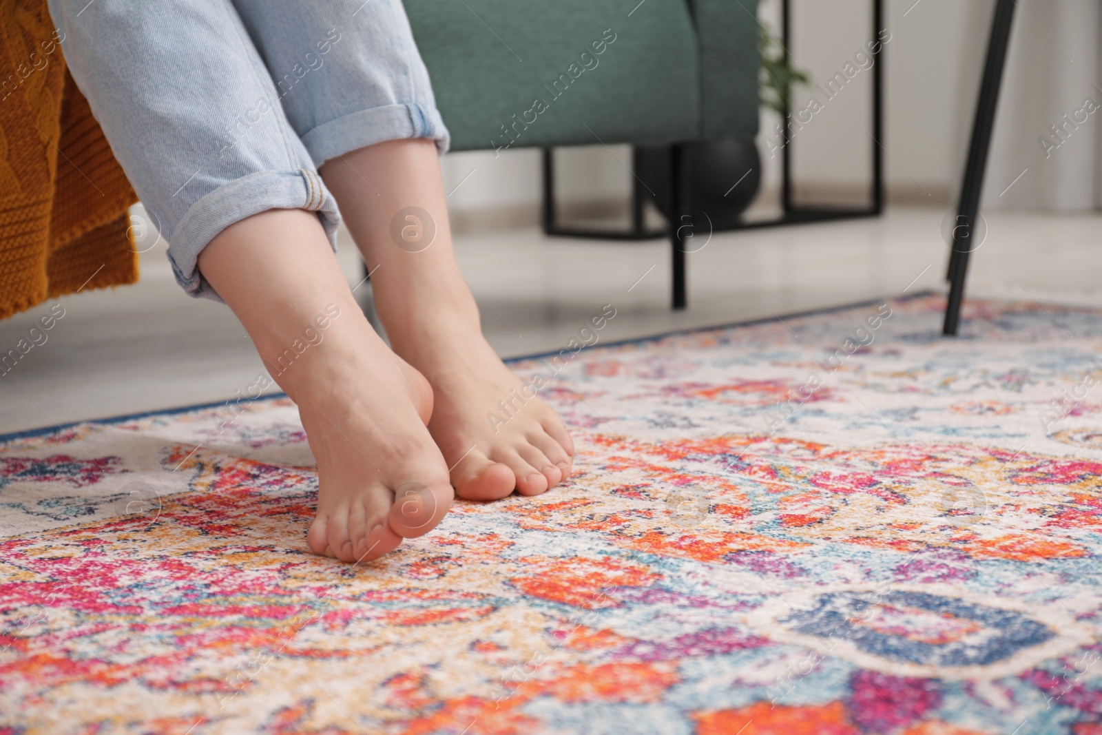 Photo of Woman sitting near carpet with pattern indoors, closeup. Space for text