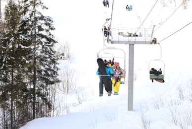 Photo of Couple using chairlift at mountain ski resort. Winter vacation