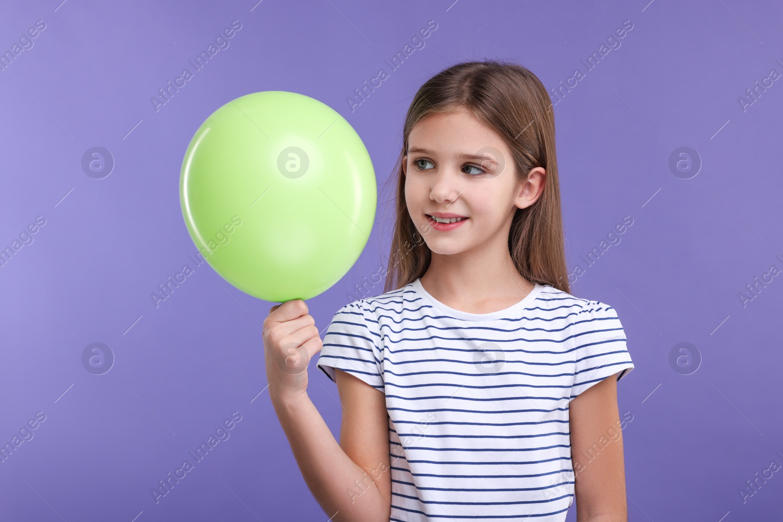 Photo of Happy girl with green balloon on violet background