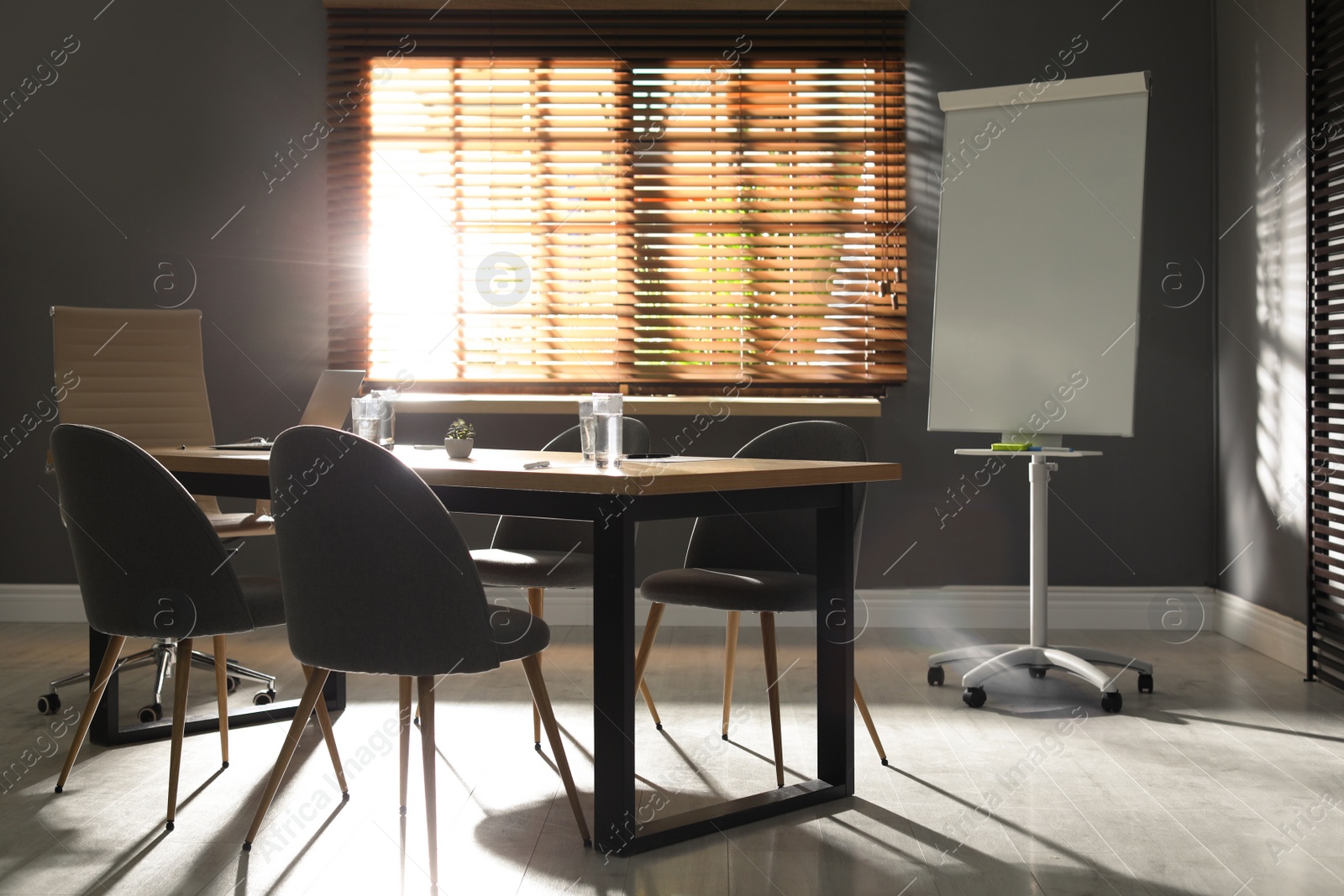 Photo of Stylish office interior with wooden table and flipchart