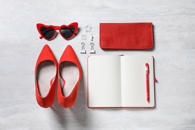 Flat lay composition with women's accessories and notebook on light table. Space for text