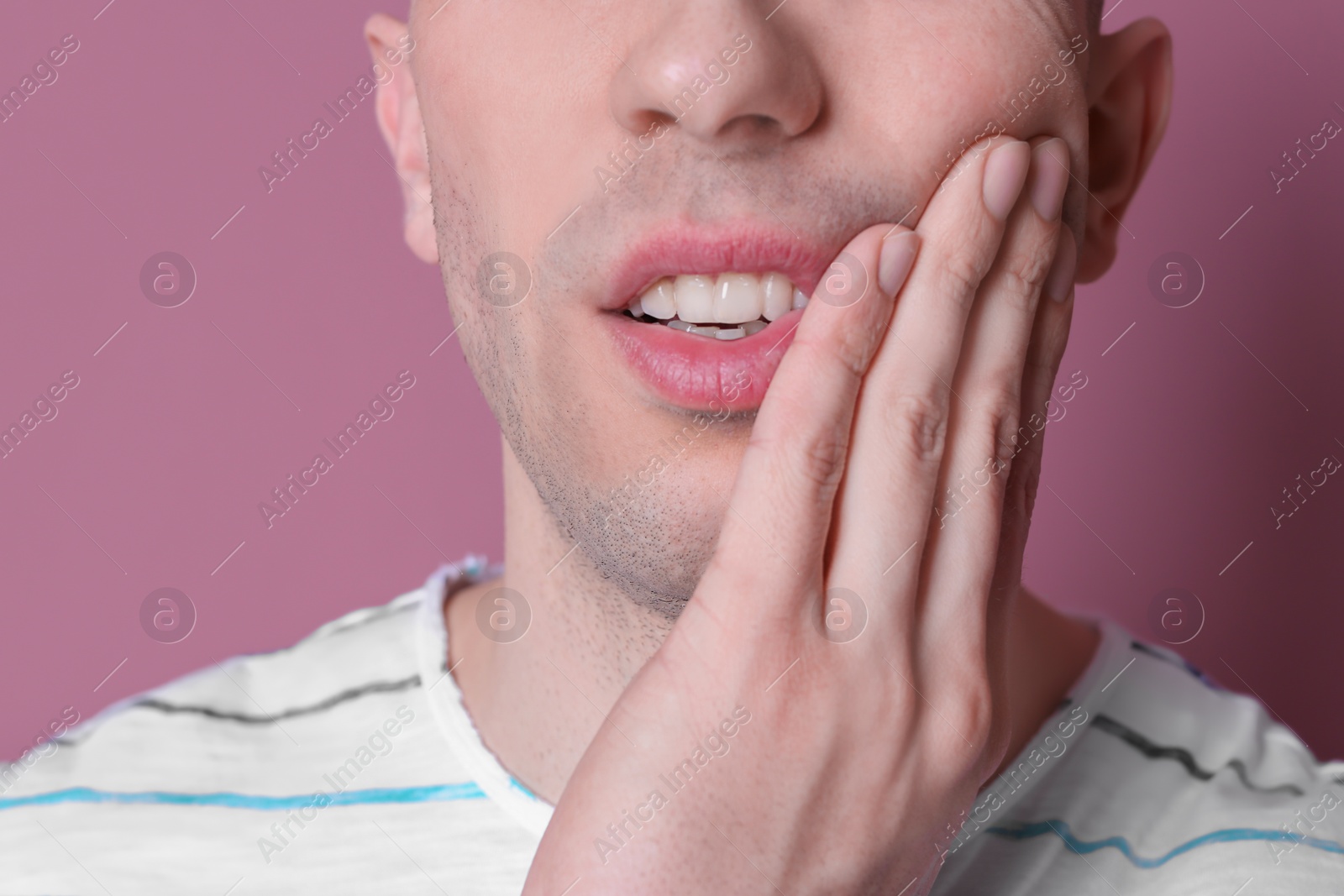 Photo of Young man with sensitive teeth on color background, closeup