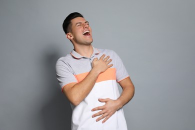 Photo of Handsome man laughing on grey background. Funny joke