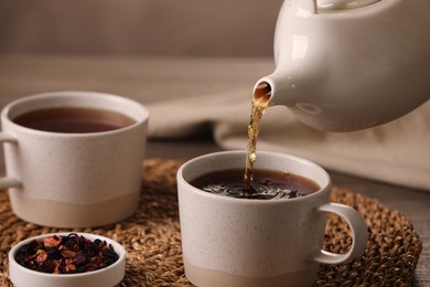 Pouring aromatic tea into cup at table, closeup