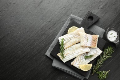 Photo of Fresh raw cod fillets, rosemary, lemon and salt on black table, flat lay. Space for text
