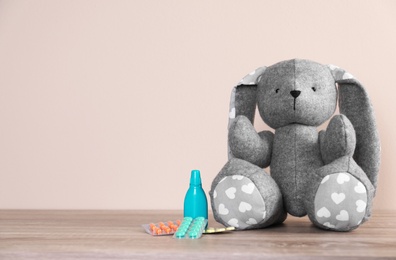 Photo of Toy bunny and medications on table against color background, space for text. Children's hospital