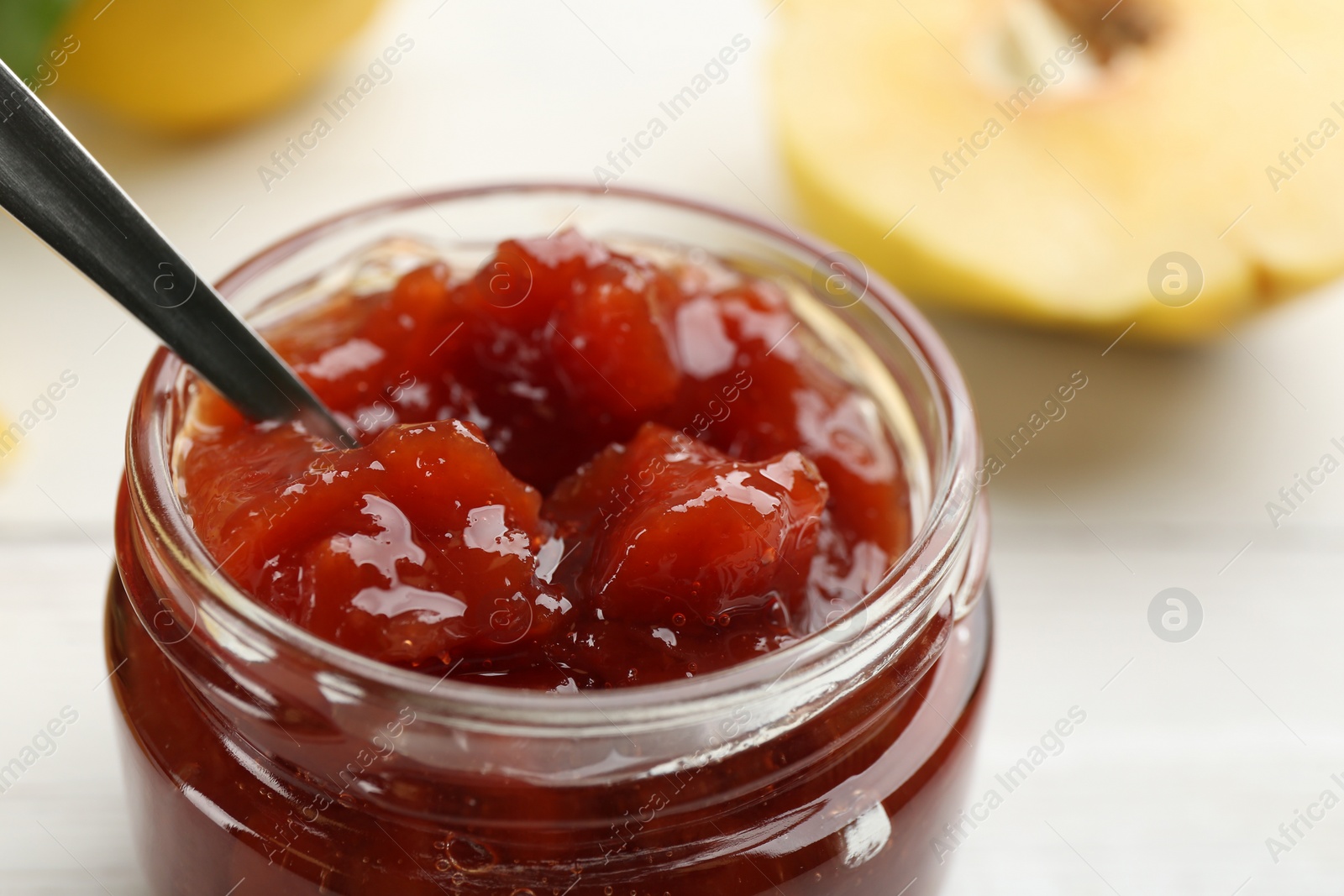 Photo of Delicious quince jam on white table, closeup